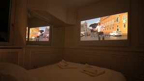 A hotel room with a bed, two pillows, and a TV screen displaying a cityscape.