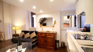 A compact living space with a kitchenette, a sofa, a dining table, and a mirror.