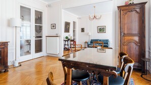 A spacious room with a wooden dining table, chairs, a chandelier, and a large cabinet.