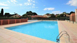 A rectangular swimming pool with a metal ladder on one side, surrounded by a tiled deck. - Maisonette T2  et parking dans résidence avec piscine (Canet-en-Roussillon)