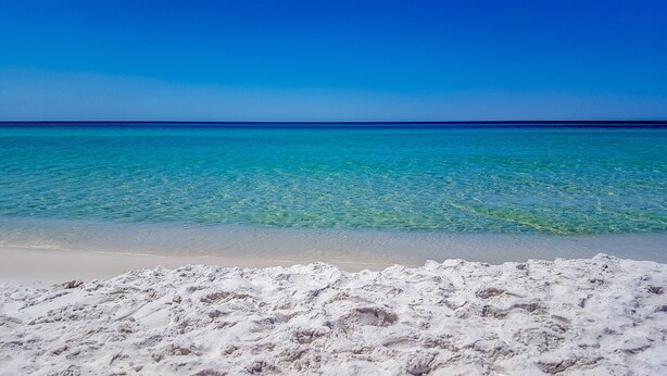 Een strand met helder turquoise water en wit zand.