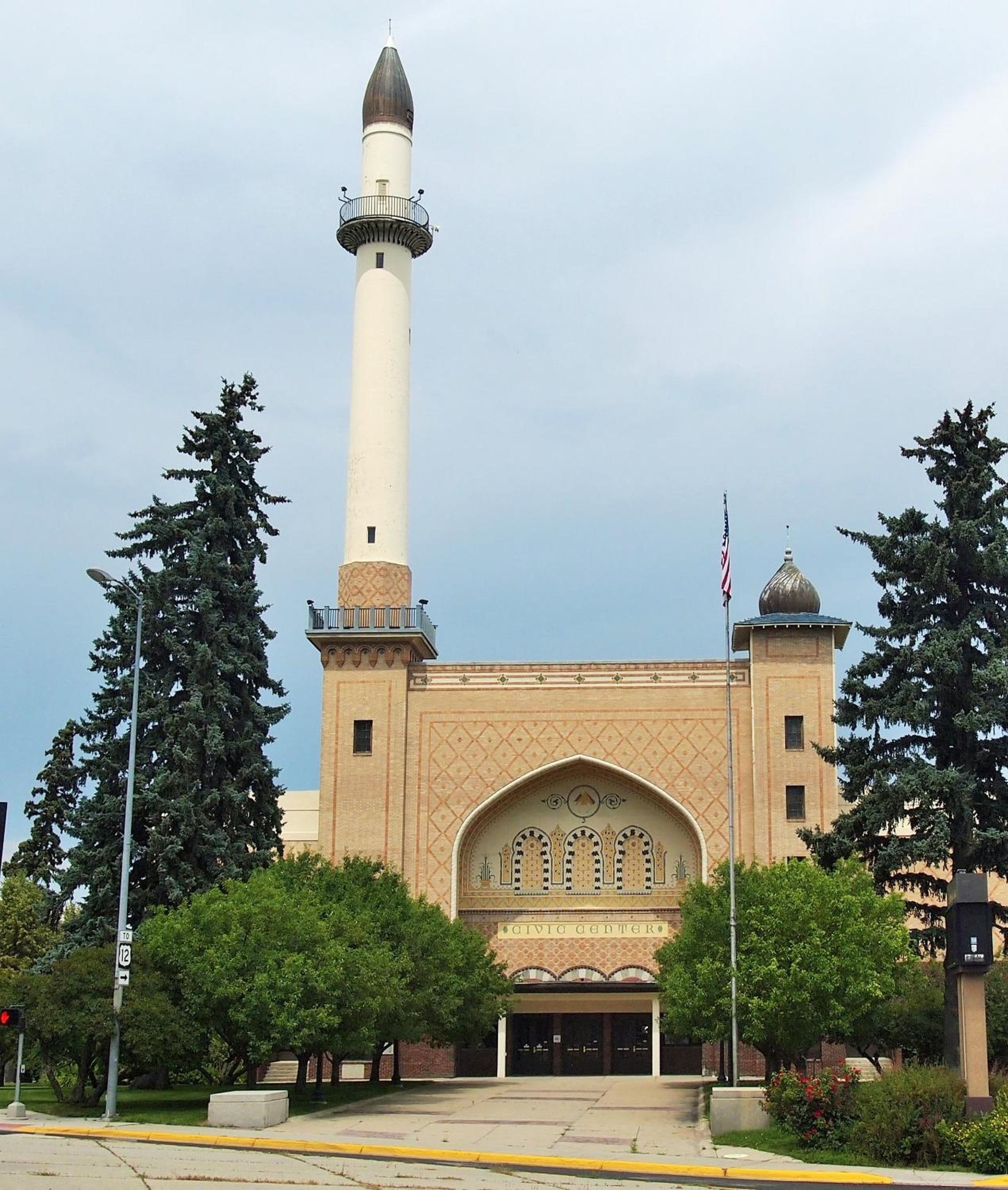 Eine Moschee mit einem hohen Minarett und einer Kuppel, sowie eine amerikanische Flagge.