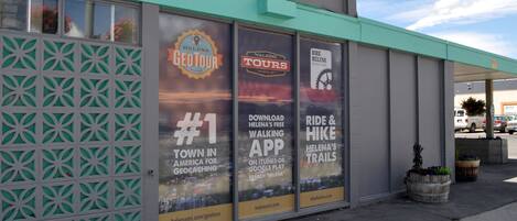 A building with large windows displaying advertisements for walking tours and a bike trail app.
