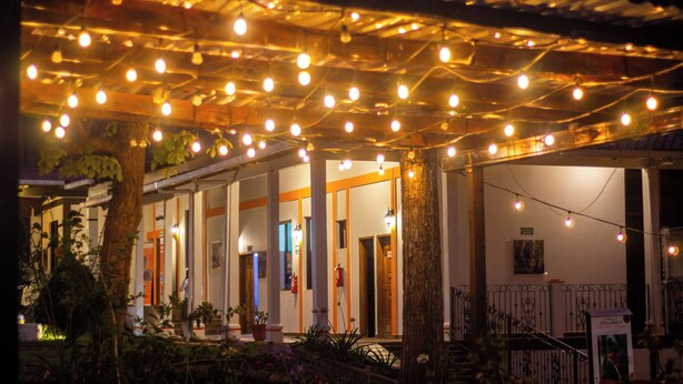 An outdoor covered area with string lights, columns, and potted plants. - Hotel Huella Lenca (Yamaranguila)