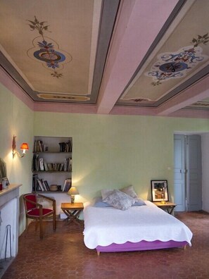 Un dormitorio con una cama, una silla, una estantería y una puerta.
