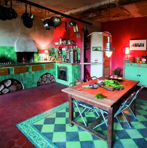 Una cocina con un salpicadero de azulejos rojos y verdes, un horno empotrado y una mesa de comedor de madera con sillas.