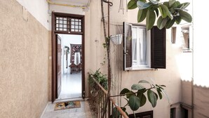 A narrow corridor with a wooden door leading to a room with a patterned rug. - Casa Linda (Roma)