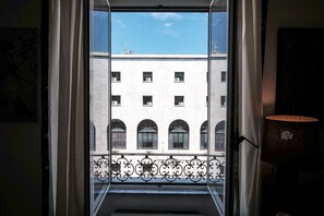 A view through a window with a balcony railing, a building with multiple windows, and a clear sky. - Casa Linda (Roma)