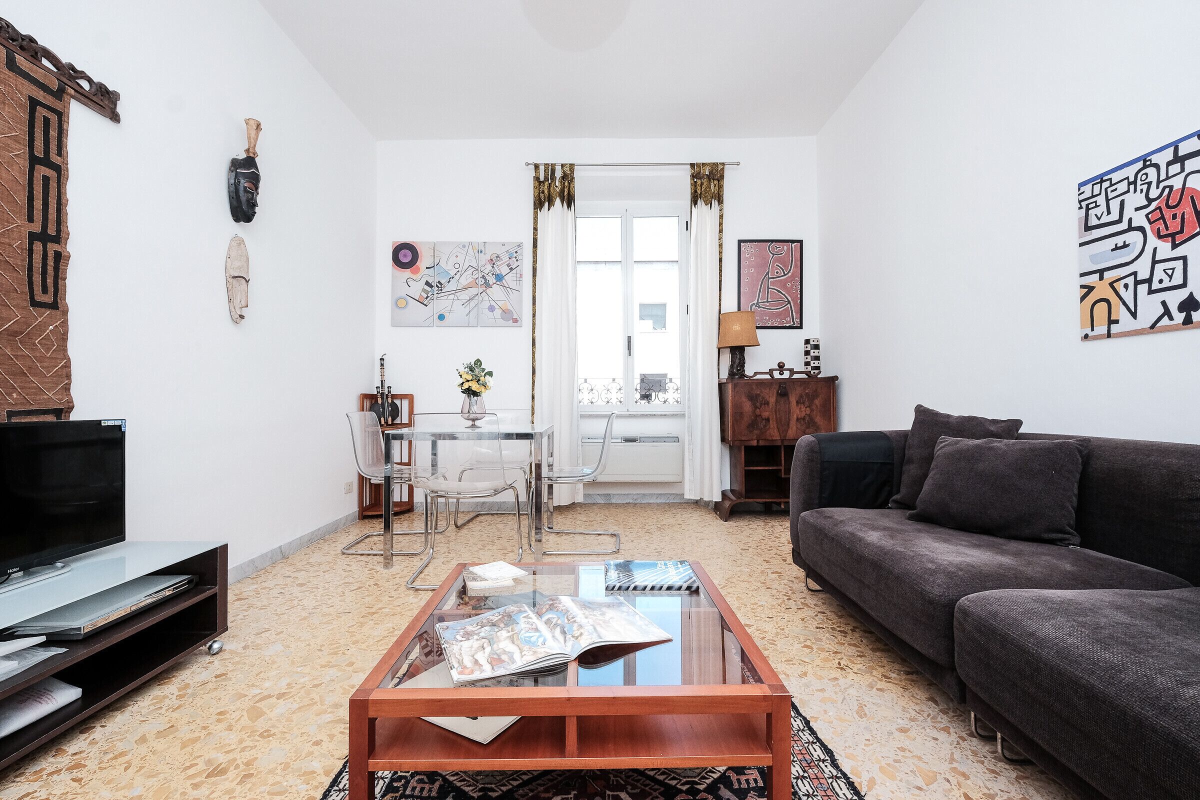 A living room with a sofa, coffee table, TV, and artwork on the walls.