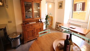 A dining area with a wooden table, chairs, a cabinet with glass doors, and a window with shutters. - The Trevi Fountain and Spanish Steps Experience (Roma)