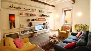 A living room with a fireplace, bookshelves, a television, and two sofas. - The Trevi Fountain and Spanish Steps Experience (Roma)