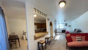 Amplia sala de estar con un sofá, una mesa de comedor y una cocina al fondo.