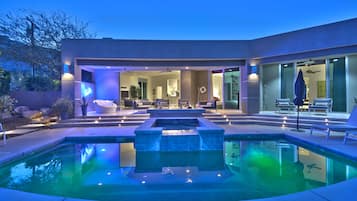 Een modern zwembadterras met een ingebouwd whirlpool, zitplaatsen en een overdekt terras.