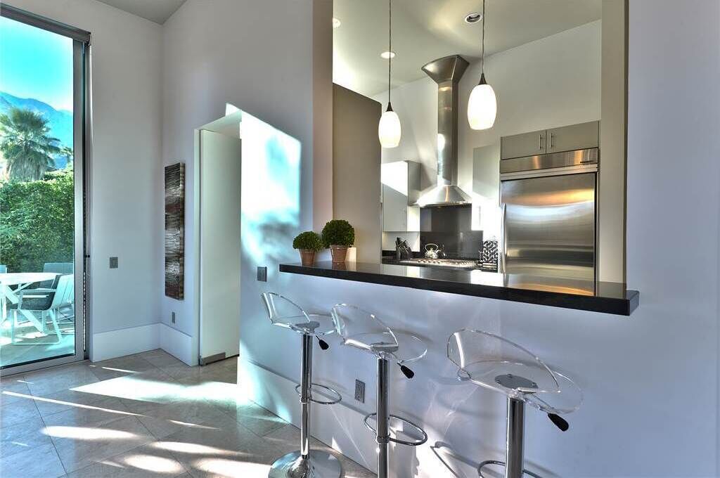 Una cocina moderna con electrodomésticos de acero inoxidable, iluminación colgante y una barra con taburetes.