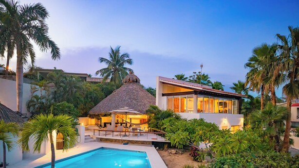 A resort with a swimming pool, a thatched-roof structure, and modern buildings. - Stunning Open-Air Villa w/ Private Pool (Huatulco)
