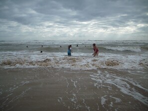 Une plage où l’on voit des gens dans l’eau et sur le rivage.