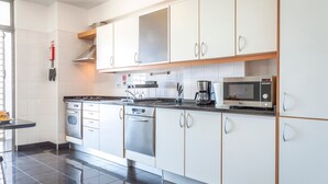 A modern kitchen with stainless steel appliances, white cabinetry, and a black countertop. - The Seaside Apartment by LovelyStay (Funchal)