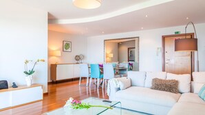 A modern living room with a sofa, a coffee table, and a dining area with chairs and a table. - The Seaside Apartment by LovelyStay (Funchal)