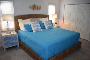Un dormitorio con una cama grande, dos mesitas de noche, un cuadro de peces en la pared y una puerta blanca.