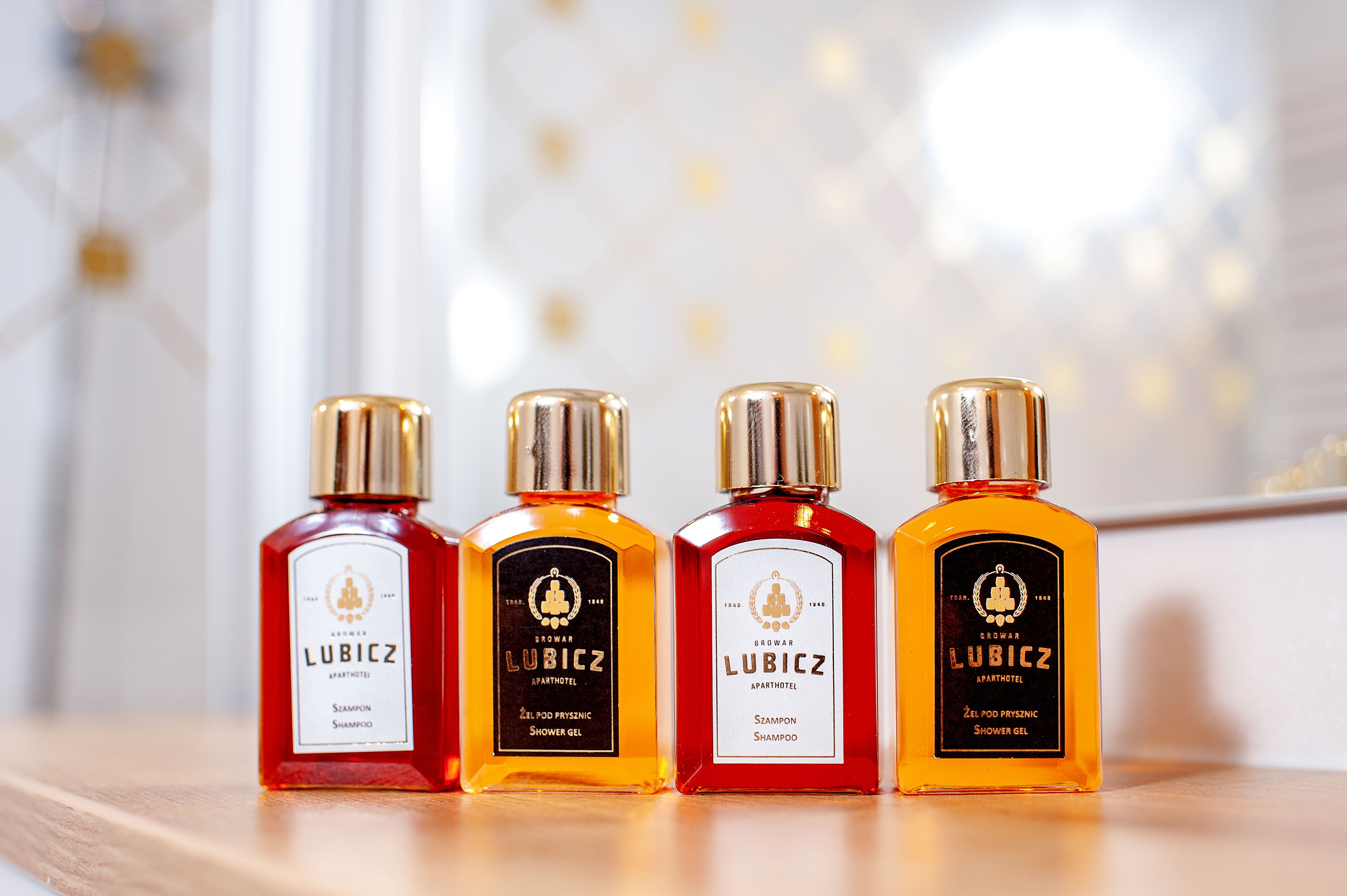 Four bottles of Lubicz shower gel on a wooden surface.