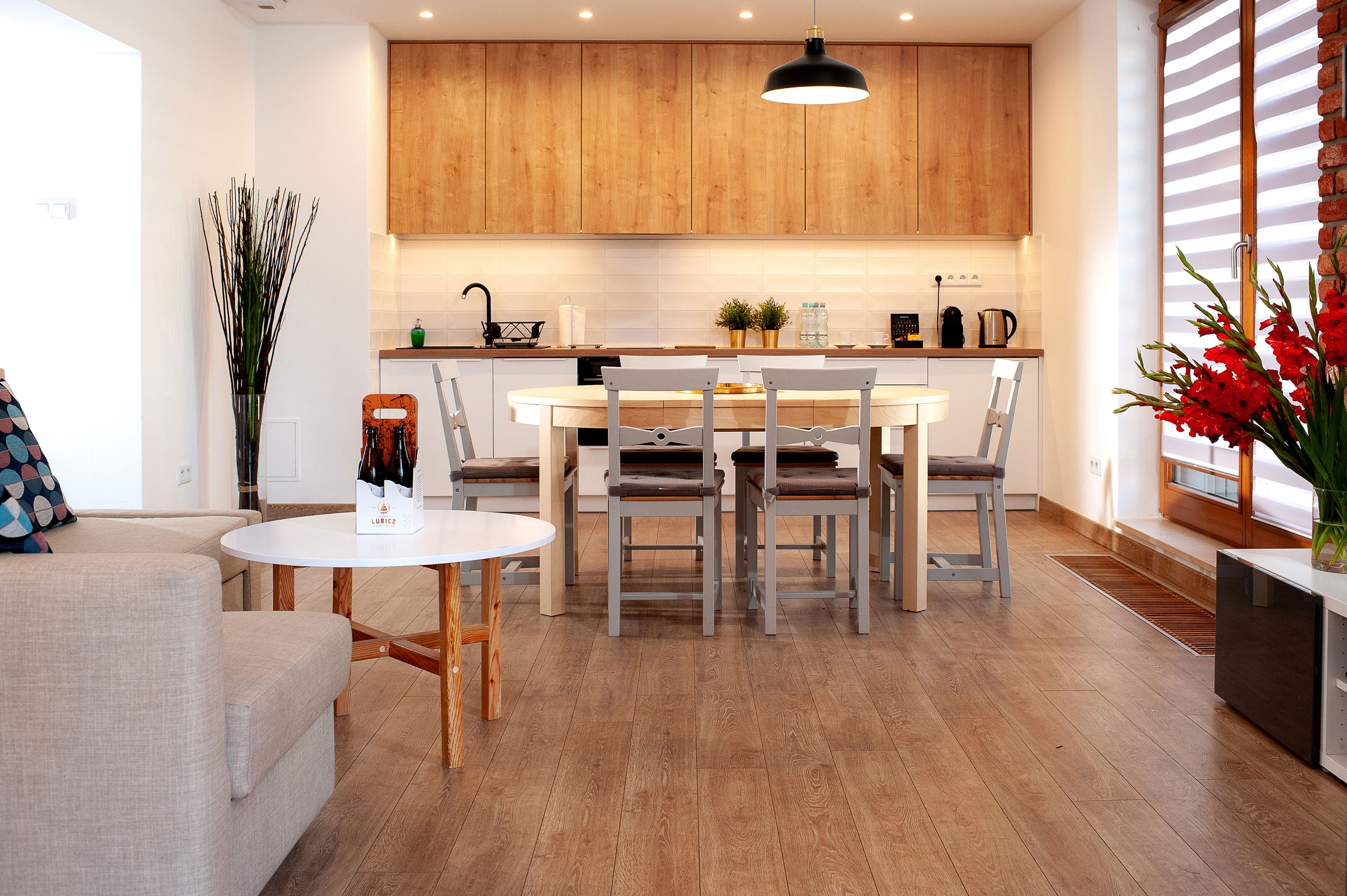 A modern kitchen with wooden cabinets, a white dining table, and a built-in oven.