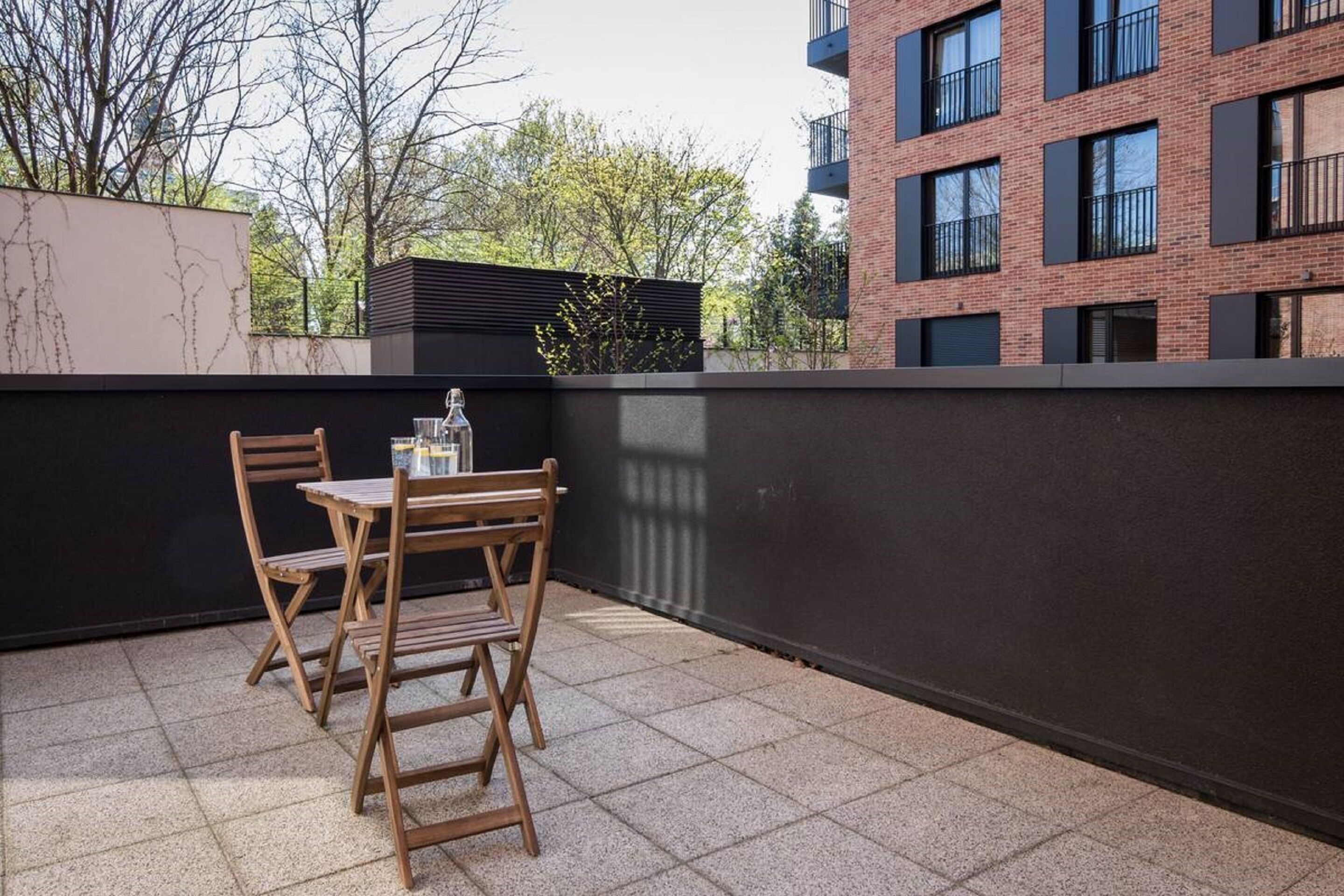 A small outdoor seating area with a table and chairs, a bottle, and a glass.