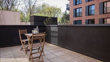 A small outdoor seating area with a table and chairs, a bottle, and a glass.