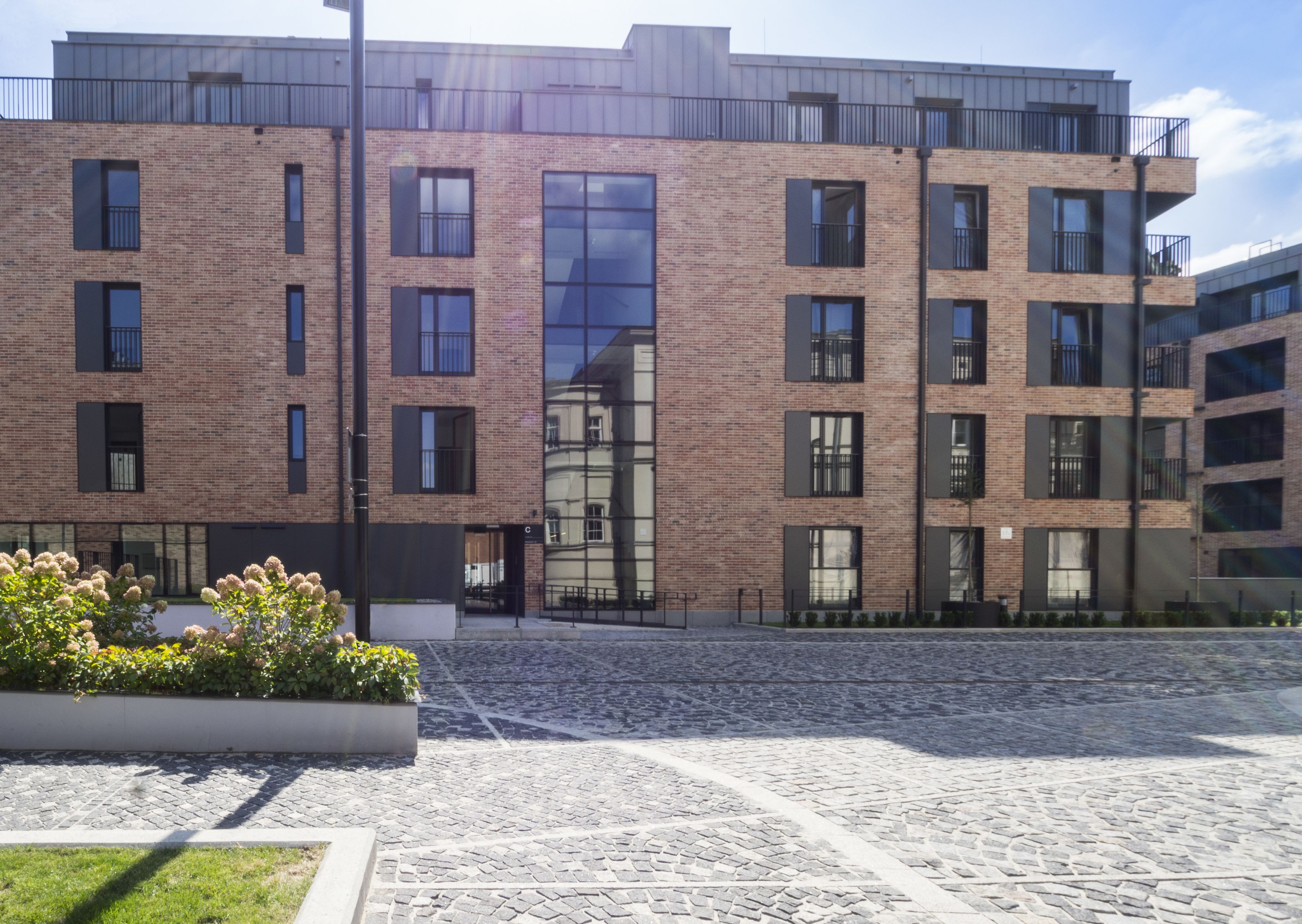 A modern multi-story building with a brick facade, large windows, and a central glass entrance.