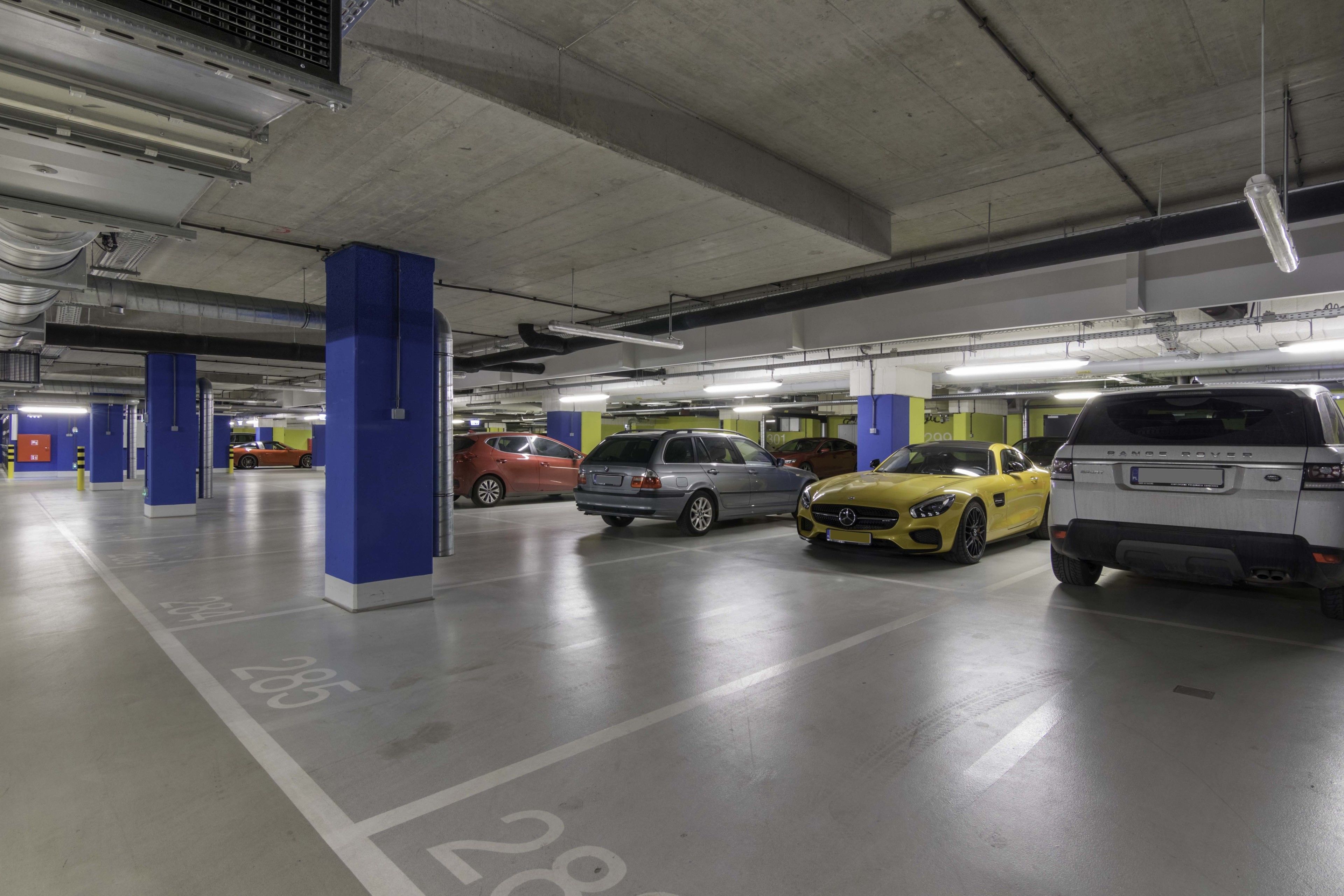 A multi-level parking garage with concrete pillars and fluorescent lighting.