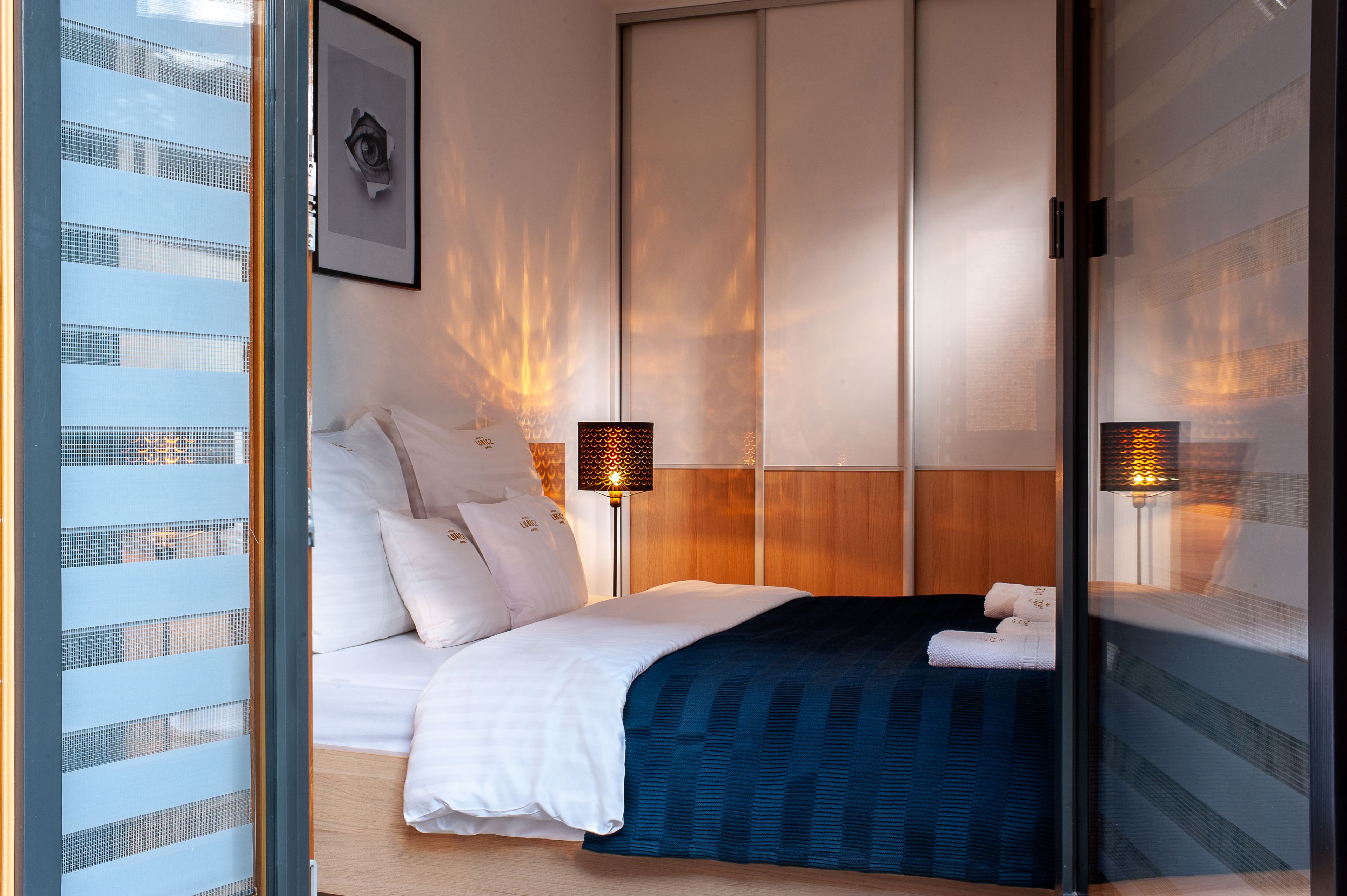 Una habitación de hotel moderna con una cama grande, un cabecero de madera y dos lámparas fijadas a la pared.