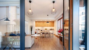 Een moderne keuken met houten kastjes, een eettafel en hanglampen.