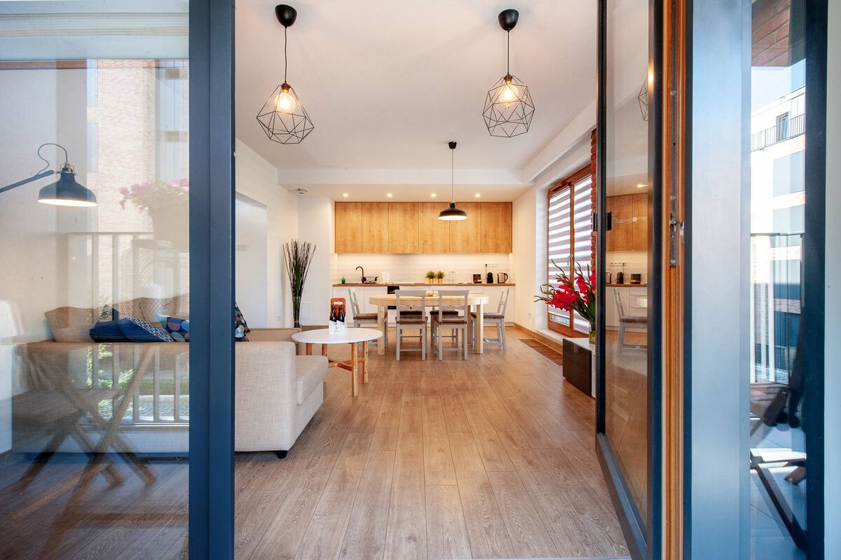 Una cocina moderna con armarios de madera, una mesa de comedor e iluminación colgante.