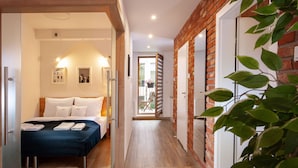 Hotelkamer met een bed, een houten vloer, een bakstenen muur en uitzicht op buiten.