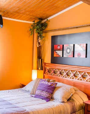 Ein Bett mit Holz-Kopfteil, ein Nachttisch und ein an der Wand befestigtes Kunstwerk.