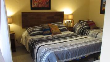 Uma cama de casal com roupa de cama listrada, uma cabeceira de madeira e duas luminárias de apoio.