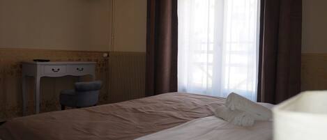 A hotel room with a bed, a desk, a chair, and a television on the wall.