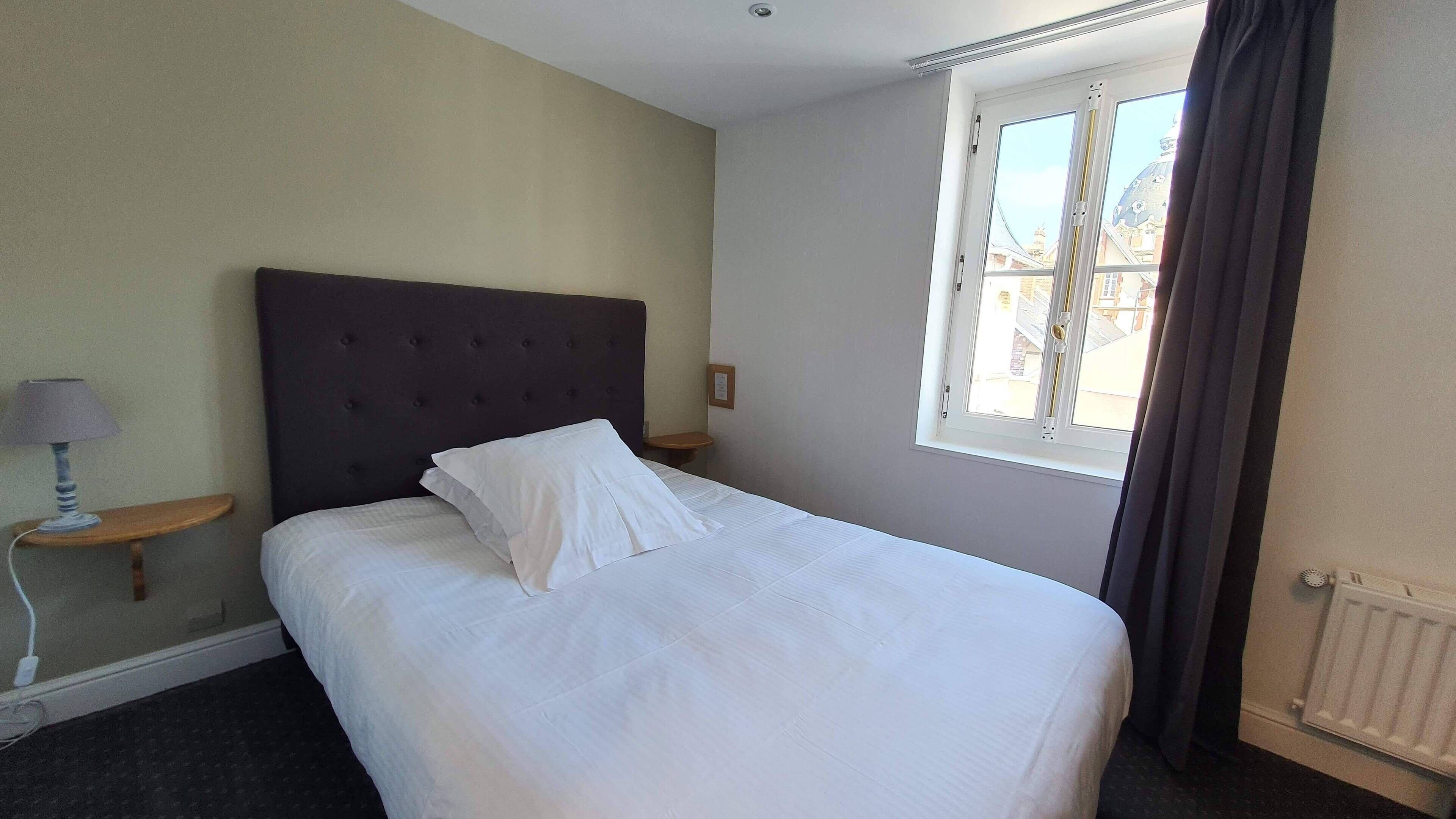 Una cama bien tendida con sábanas blancas en una habitación de hotel.