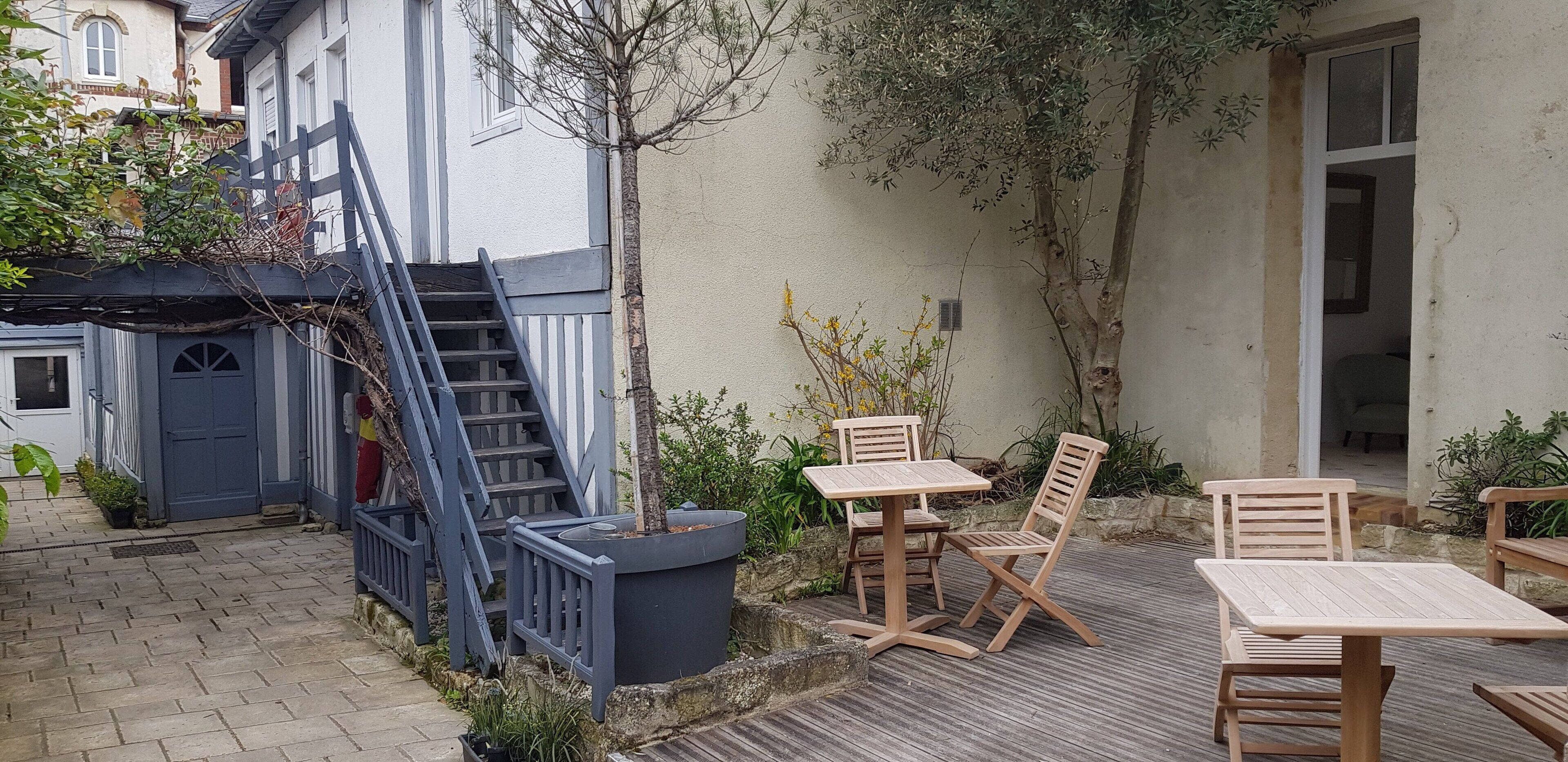 Un patio con escaleras de madera, asientos exteriores y una planta en maceta.
