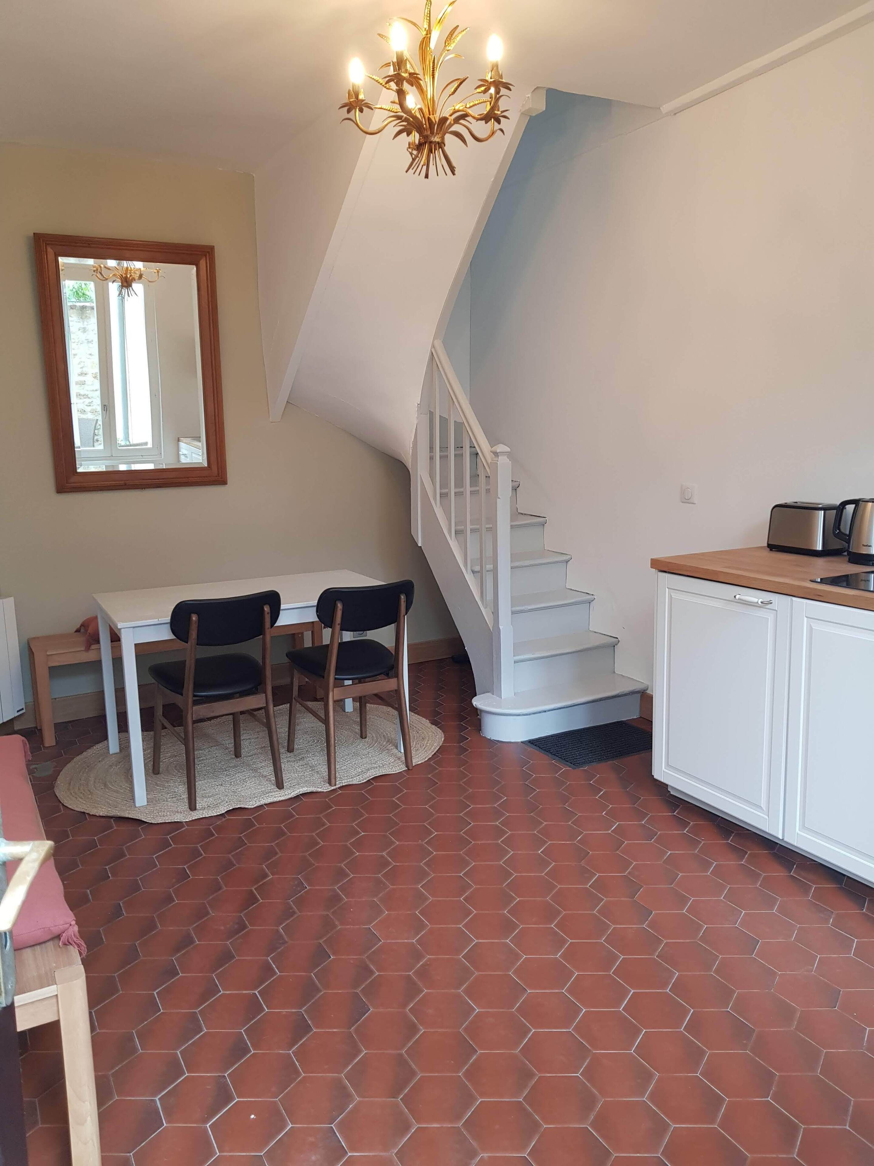 Una cocina compacta con comedor, una escalera y un espejo.