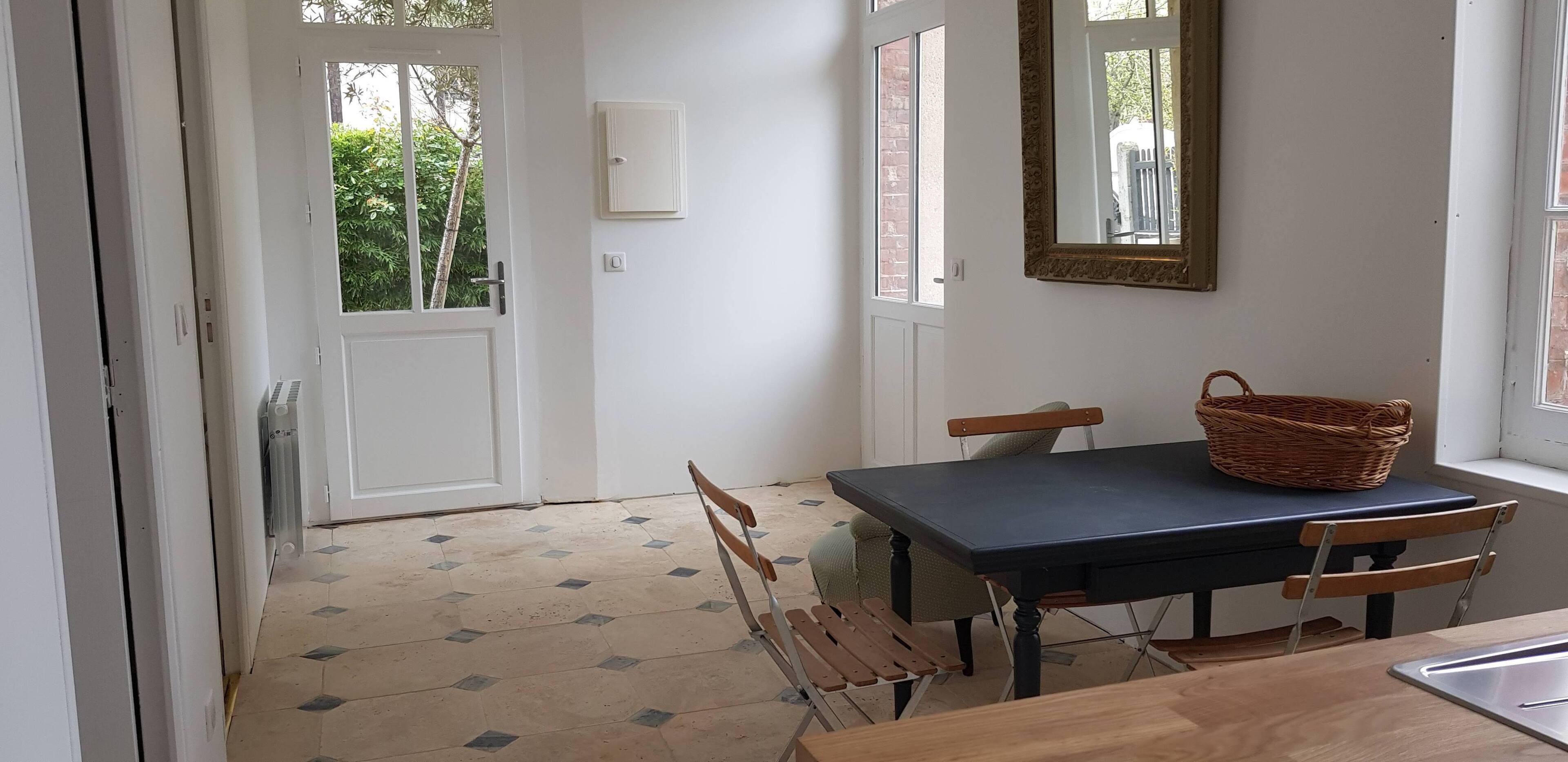 A dining area with a table, chairs, a basket, and a window with a mirror.