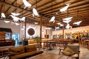 A spacious indoor area with wooden tables and benches, a reception desk, and hanging pendant lights. - Tamarina Bed and Beyond (Koh Samui)