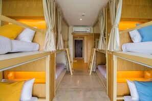 A bunk room with wooden bunk beds, curtains, and an air conditioning unit. - Tamarina Bed and Beyond (Koh Samui)