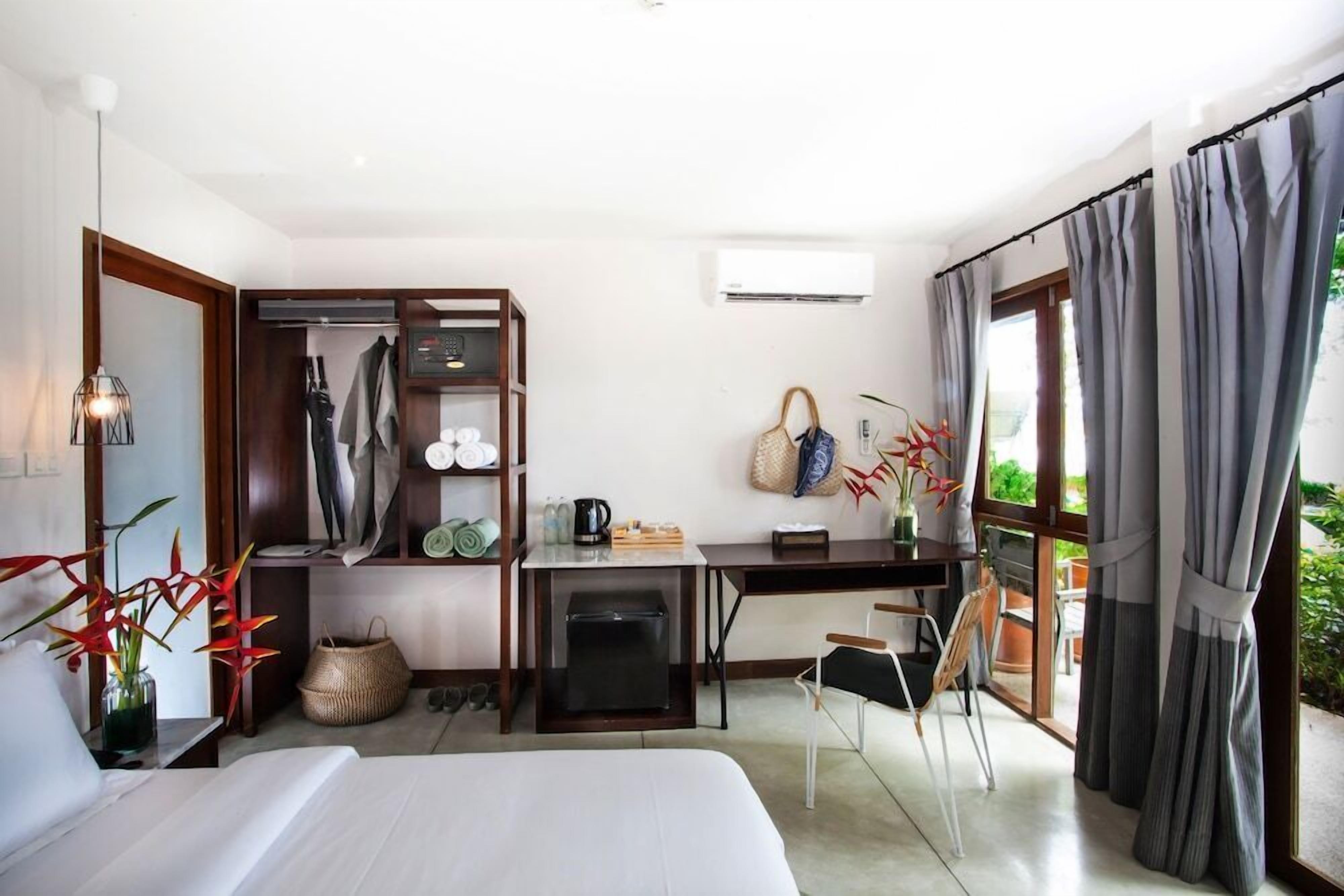 A hotel room with a bed, desk, wardrobe, and a view of the outdoors.