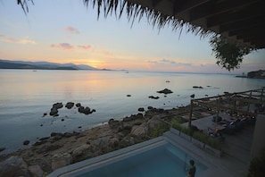 A pool area with a view of the sea and distant mountains during sunset. - Tamarina Bed and Beyond (Koh Samui)