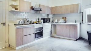 Una cocina moderna con armarios de madera, microondas, estufa y diversos electrodomésticos.