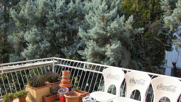A balcony with potted plants, Coca-Cola branded chairs, and a tiled floor. - Ca' Concordia Venice (Mestre)