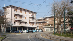 A multi-story building with balconies, a parking lot with several cars, and a curved road with tram tracks. - Ca' Concordia Venice (Mestre)