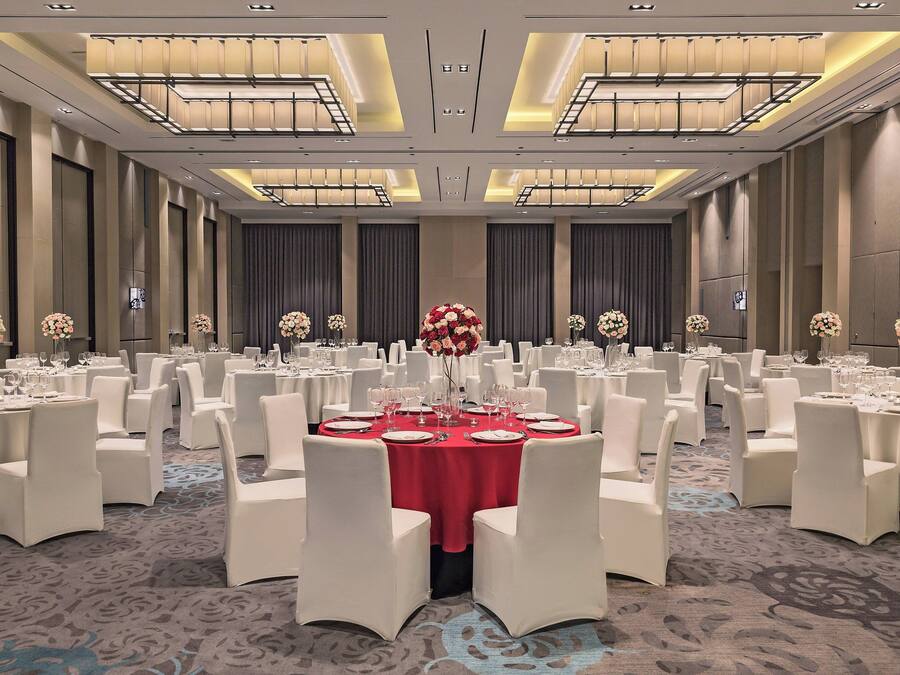 A banquet hall with round tables set for dining, white chairs, and floral centerpieces.