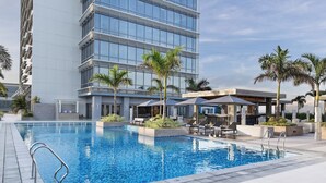 Um hotel moderno com piscina, área de estar ao ar livre e palmeiras.