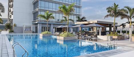 Un hotel moderno con piscina, mobiliario exterior y palmeras.